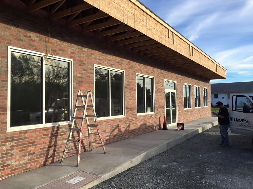 Worker from Dave's Glass Co. replacing windows alongside a storefront